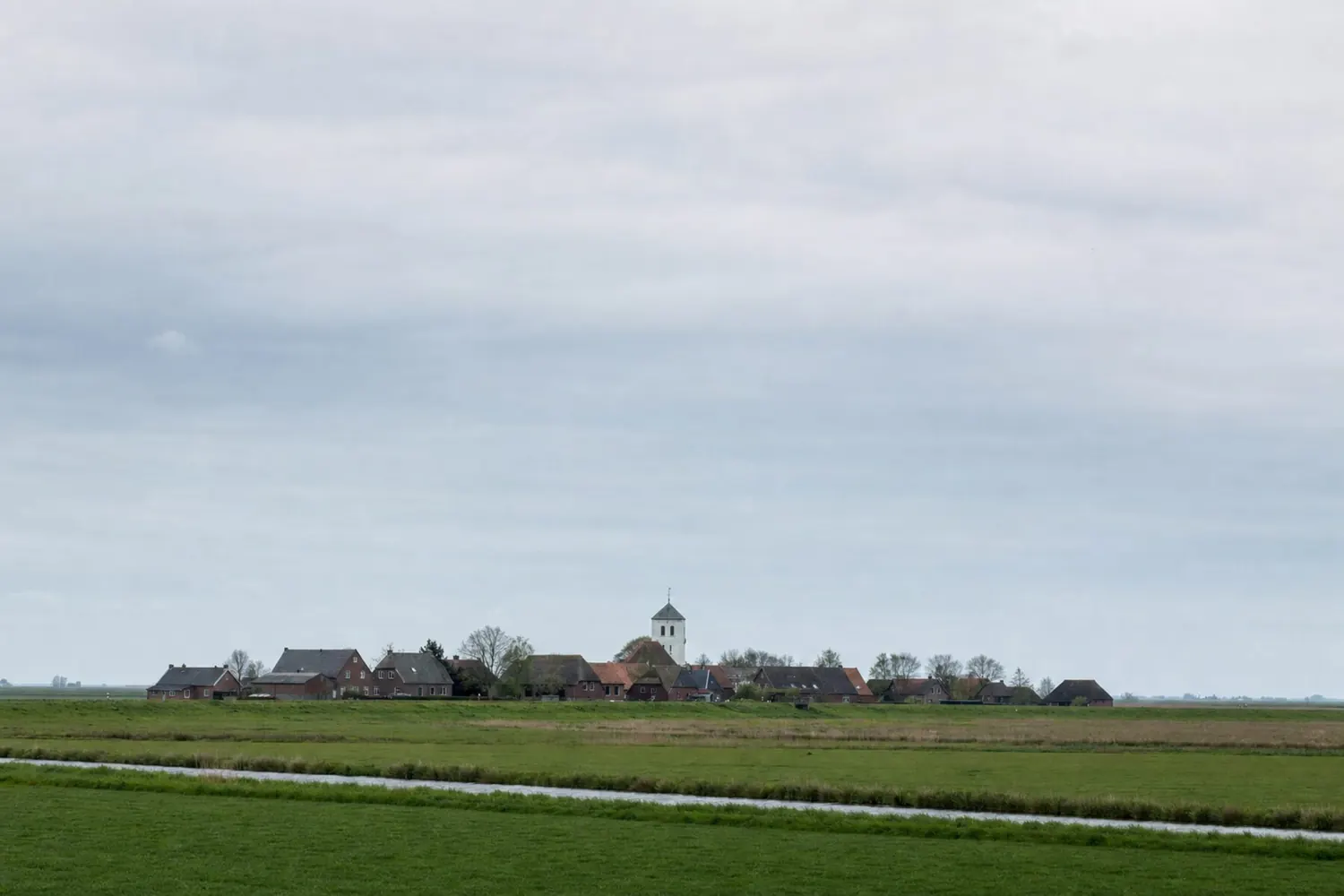 Ein Marschdorf liegt flach in der Landschaft