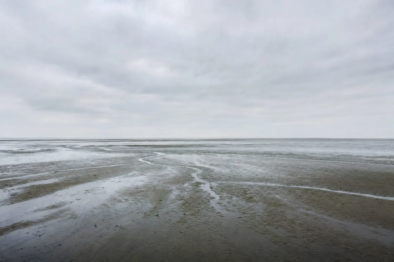 Das Wattenmeer bei ablaufendem Wasser unter bedecktem Himmel